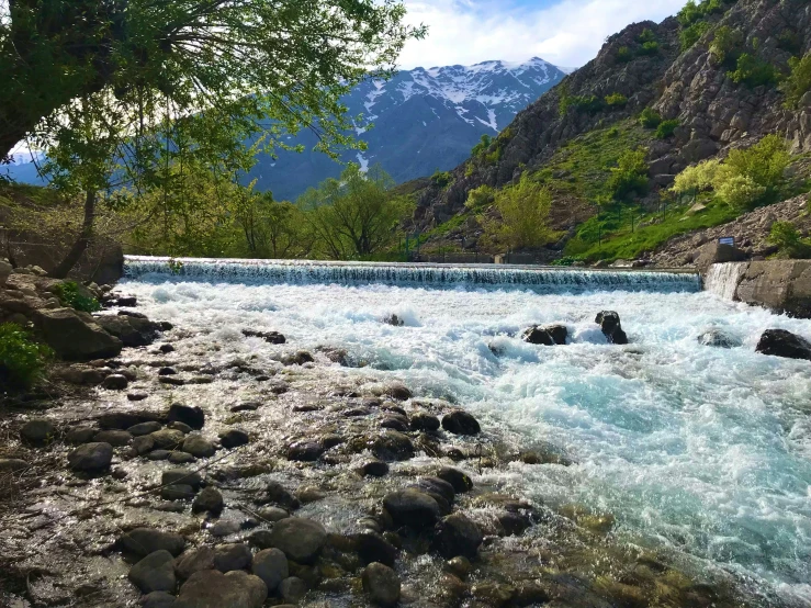 rocks next to a river with mountains in the background