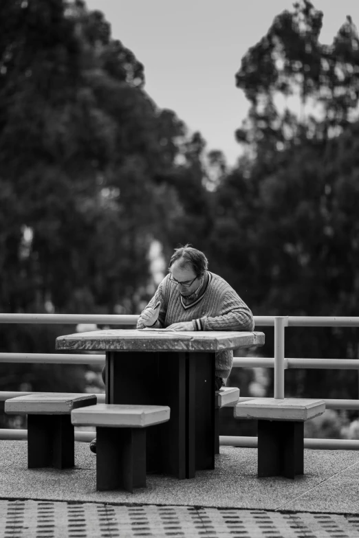 black and white pograph of man leaning over table in park