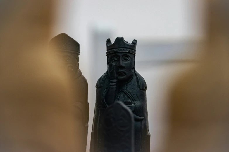 a black figurine wearing a crown stands in front of a window