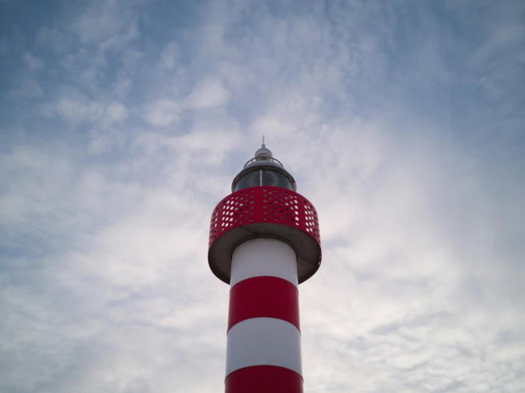 a red and white lighthouse against a cloudy sky