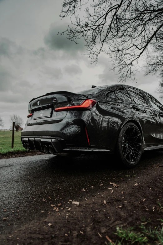 the rear view of a gray sports car driving on a rainy road