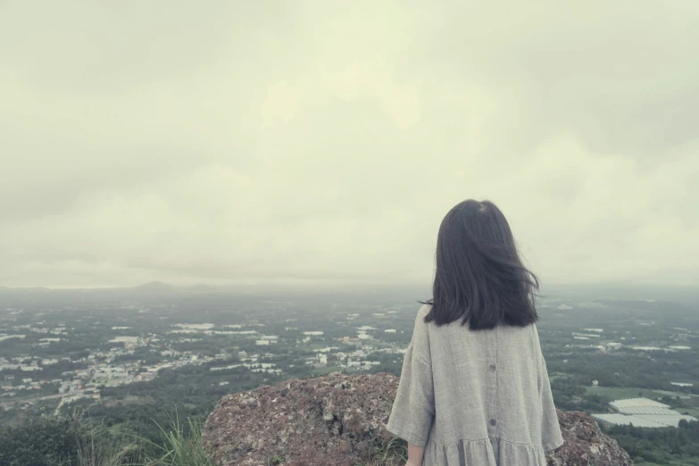 a person stands in front of a cloudy sky and overlooks the valley below