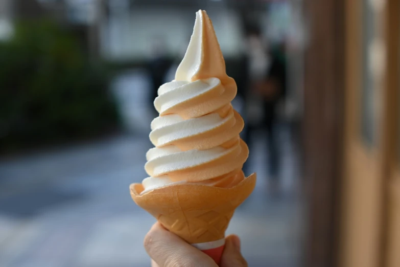 a hand is holding an orange ice cream