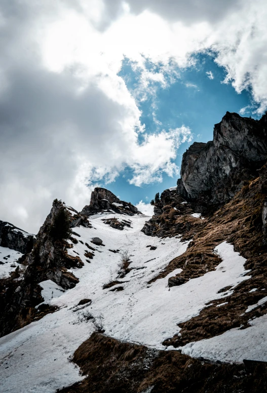 a rocky mountain with snow in the foreground