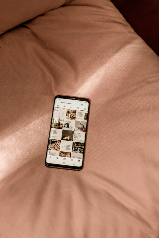 an iphone sitting on the covers of bed in a bedroom