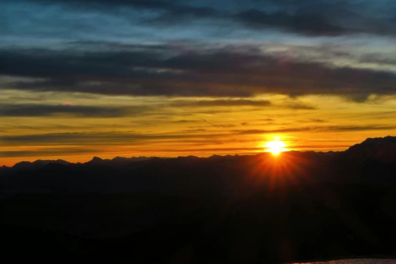 the sun is setting over the mountains and water