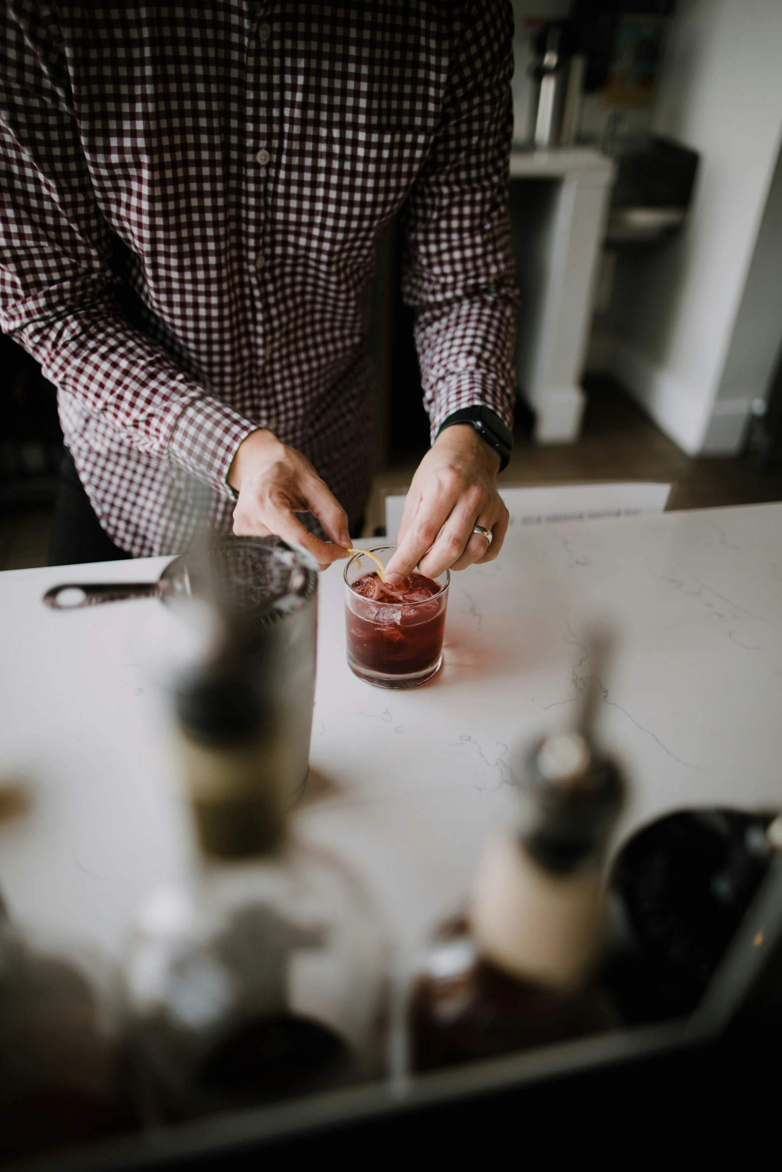 a man that is standing in the kitchen putting soing in a jar