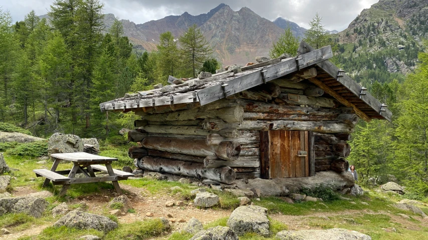 a stone cabin sits next to some trees and rocks