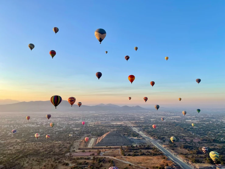  air balloons fill the sky over a town