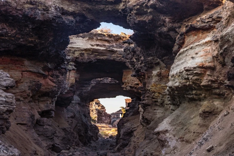 a natural rock arch surrounded by cliffs on a sunny day