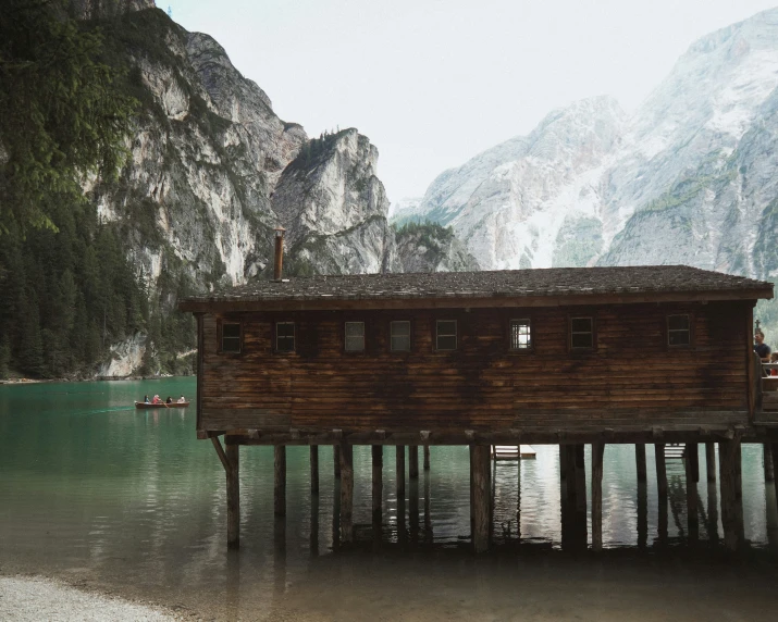 a boathouse sitting in a lake surrounded by mountains