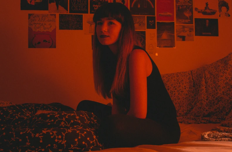 a woman sitting on top of a bed next to a pillow