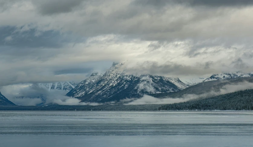 some snow and mountains under cloudy skies