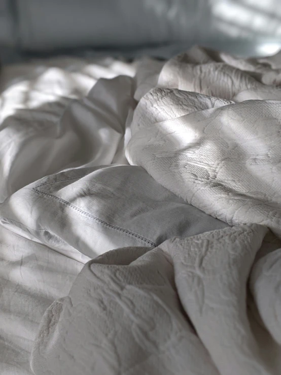 a bed with white comforters and blankets on top of it