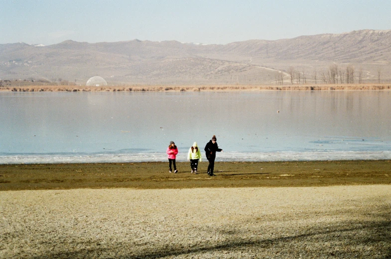 three people on the beach flying a kite