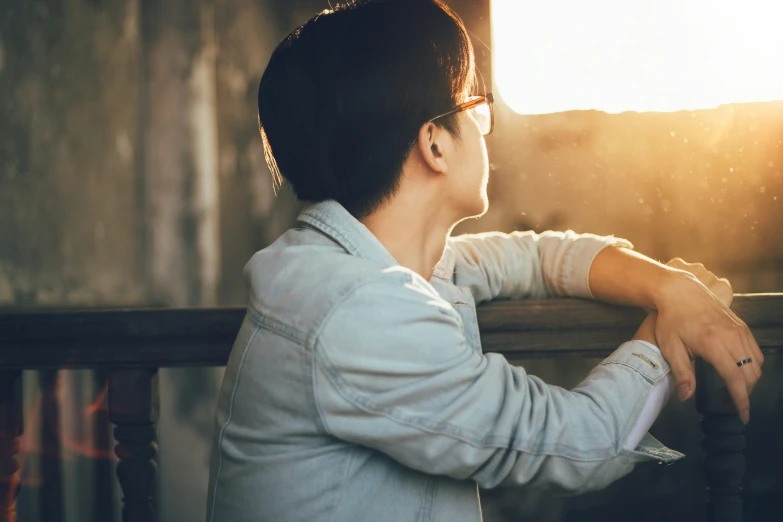 a man is sitting on a bench at sunset