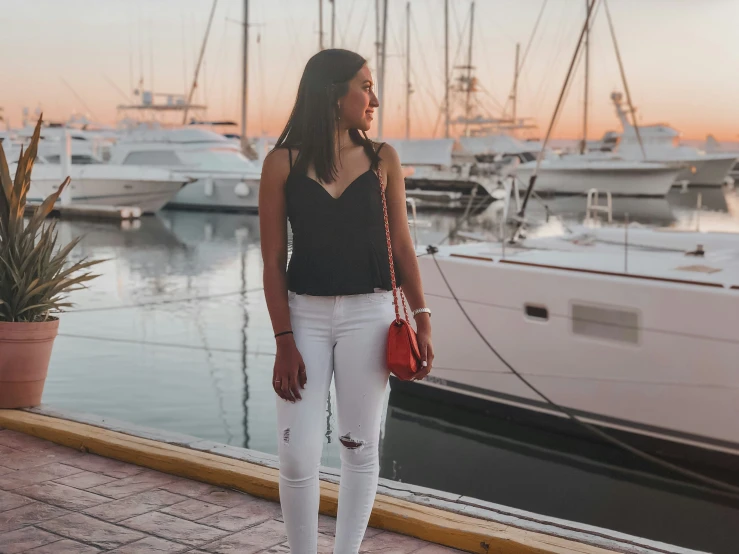 a young woman stands on a dock in front of boats