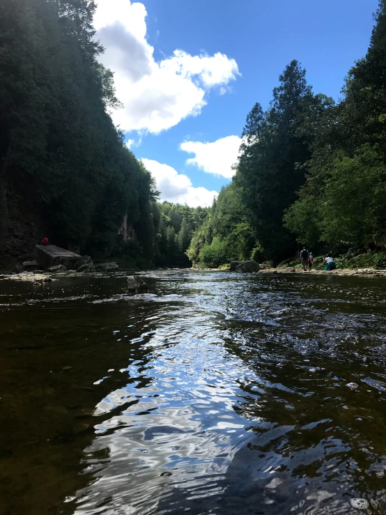 view from the bottom of a river of people standing on the rocks in a river