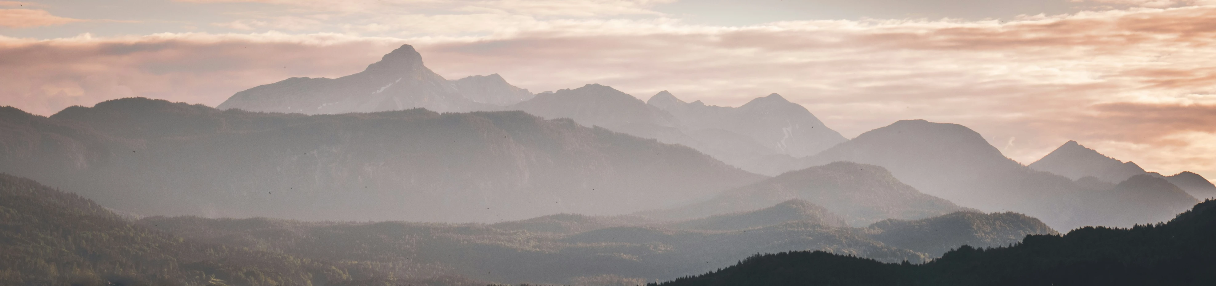 the mountains are covered in fog as the sun sets