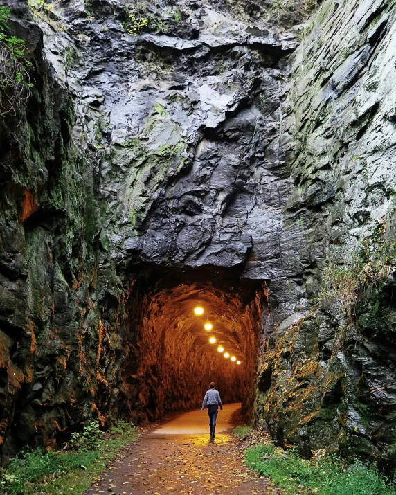 a person walks out from a tunnel that is dark with some lights on it