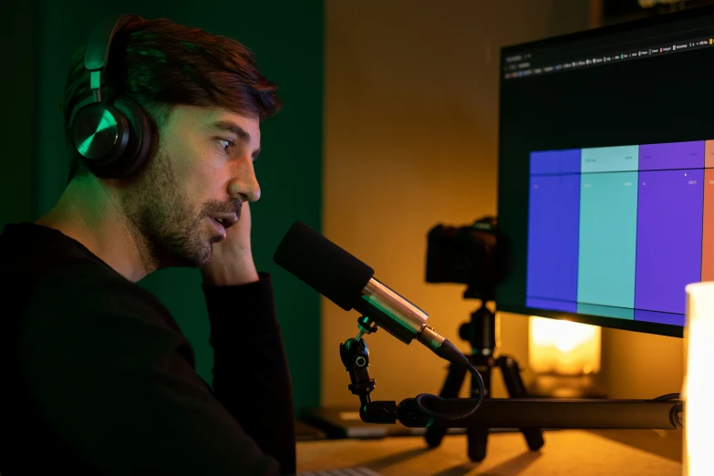 a man in a black shirt listening to music on a tv and holding his headphones