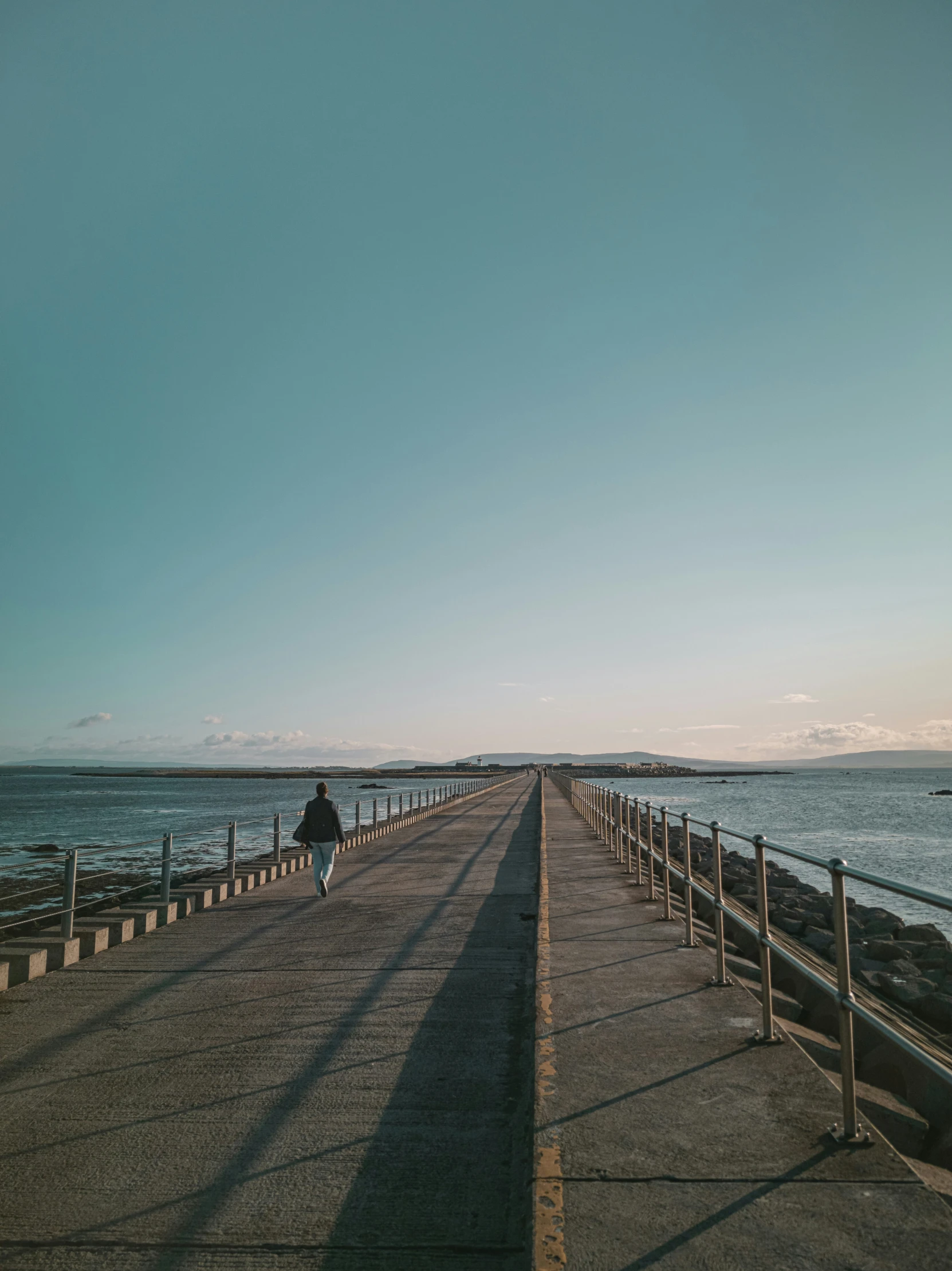 a person walks along a boardwalk by the ocean