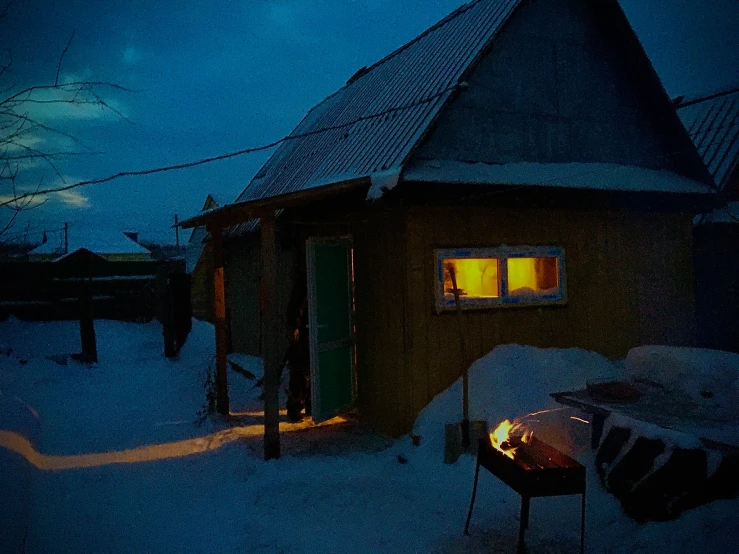 a cabin is lit up on a snowy day