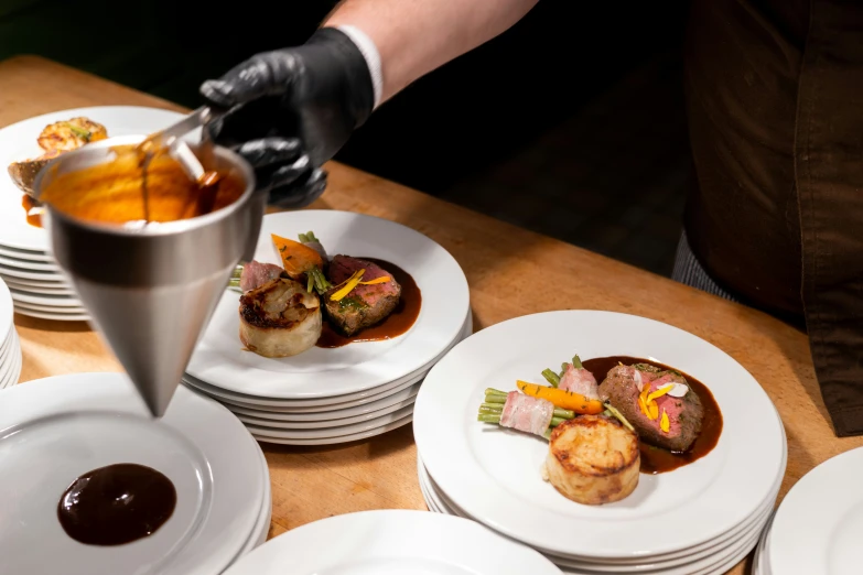 a chef is drizzling sauce on a selection of dishes