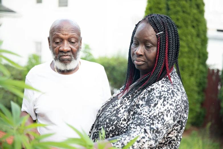 an older african couple are standing in their yard