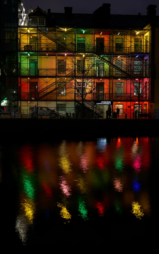 a neon building and water reflect as it lights up at night