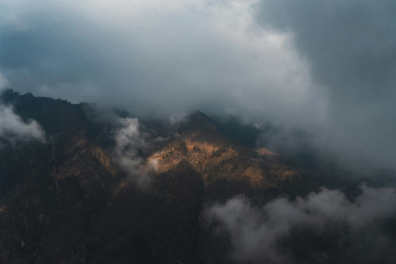 mountain peak in a cloud filled sky with sun coming through