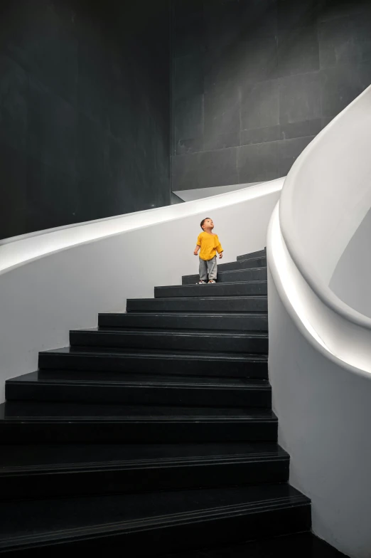 a  standing at the top of a set of stairs in front of a white curved stair case