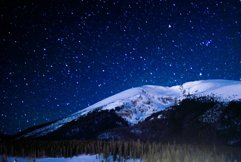 the stars are shining in the night sky over the mountains