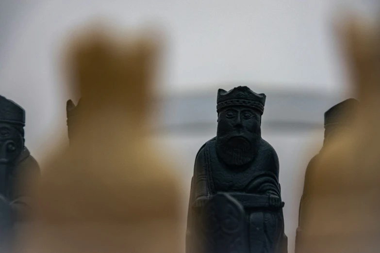 a row of carved statues of men in front of a blurry white wall