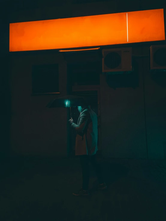 a man in a dark room at night looking out a lit up door