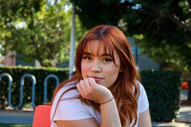 a woman sitting at an orange chair with her hand on her chin