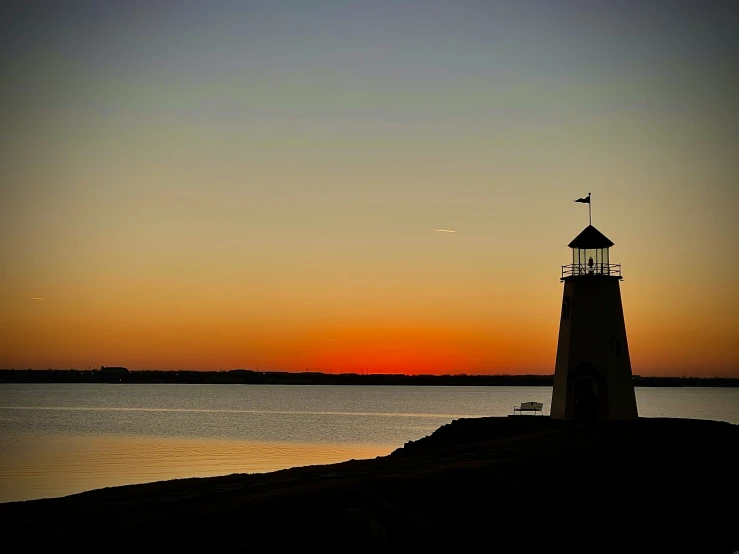 the sun is setting at a lighthouse by the sea