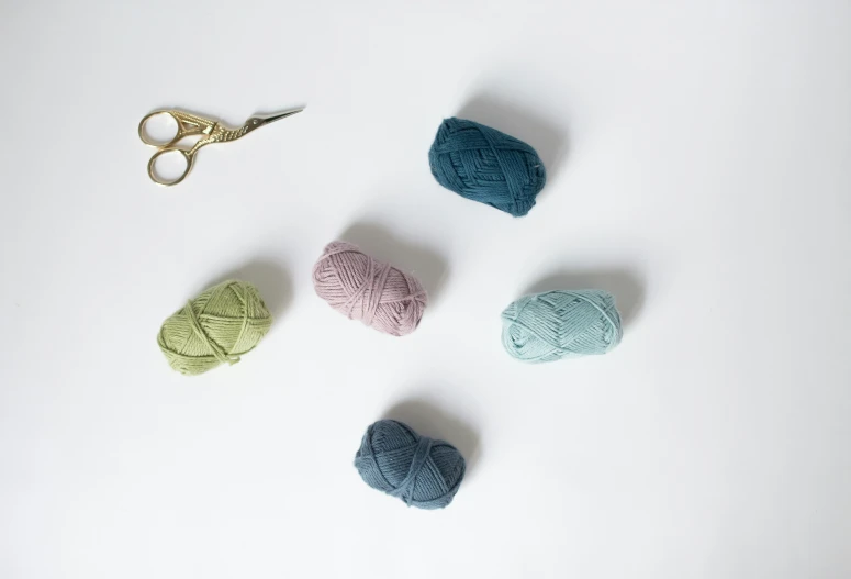 three balls of yarn next to a pair of scissors