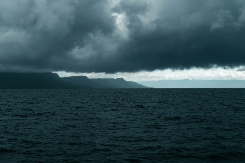 clouds gathering over a body of water and mountains