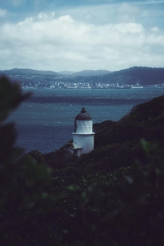 a white light house in front of a lake