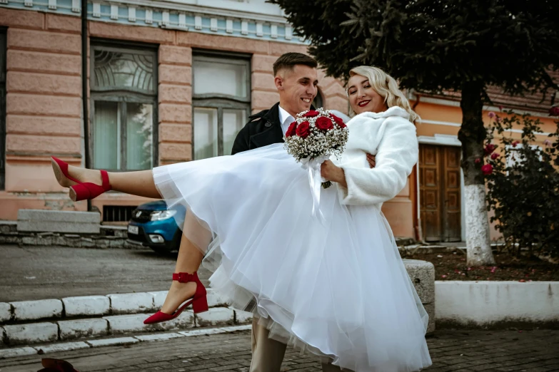 a man carrying a woman who is wearing red shoes