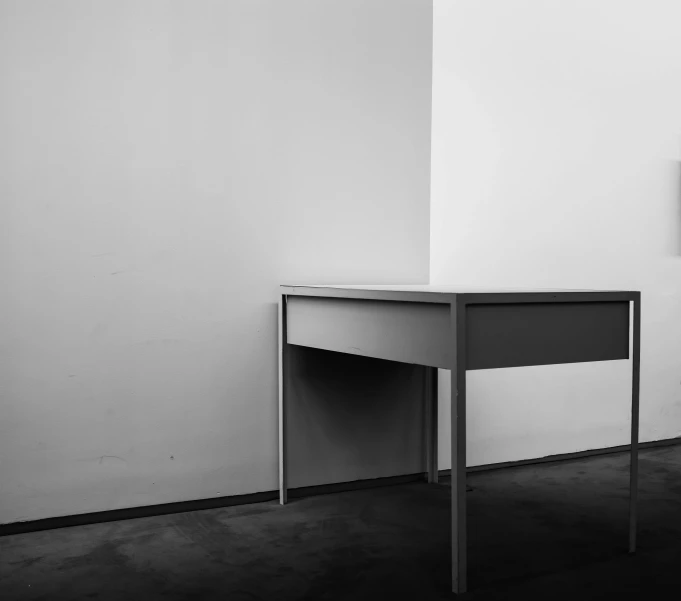 a desk sitting in a corner by the wall