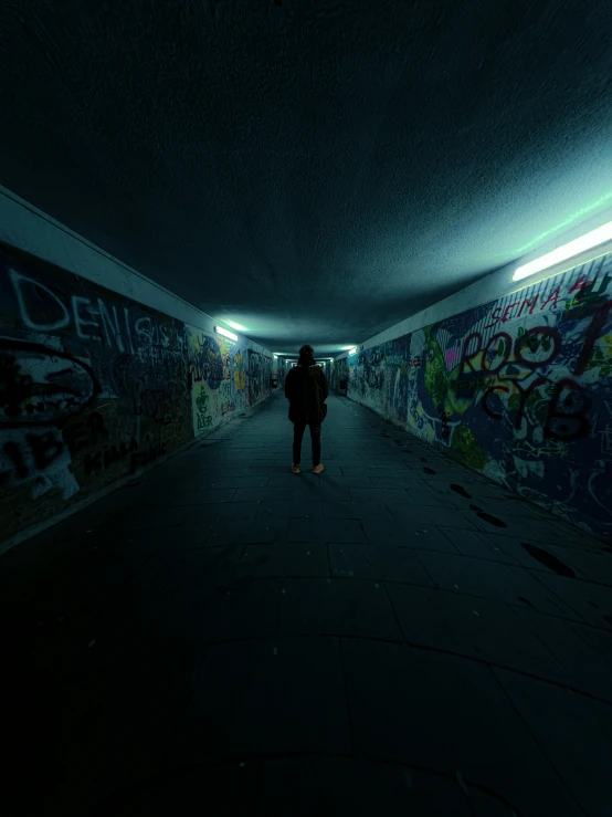 a man walks down a hallway covered in graffiti