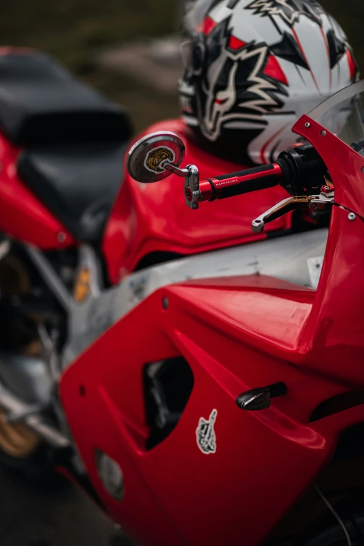 a red motorcycle parked next to a grass covered field