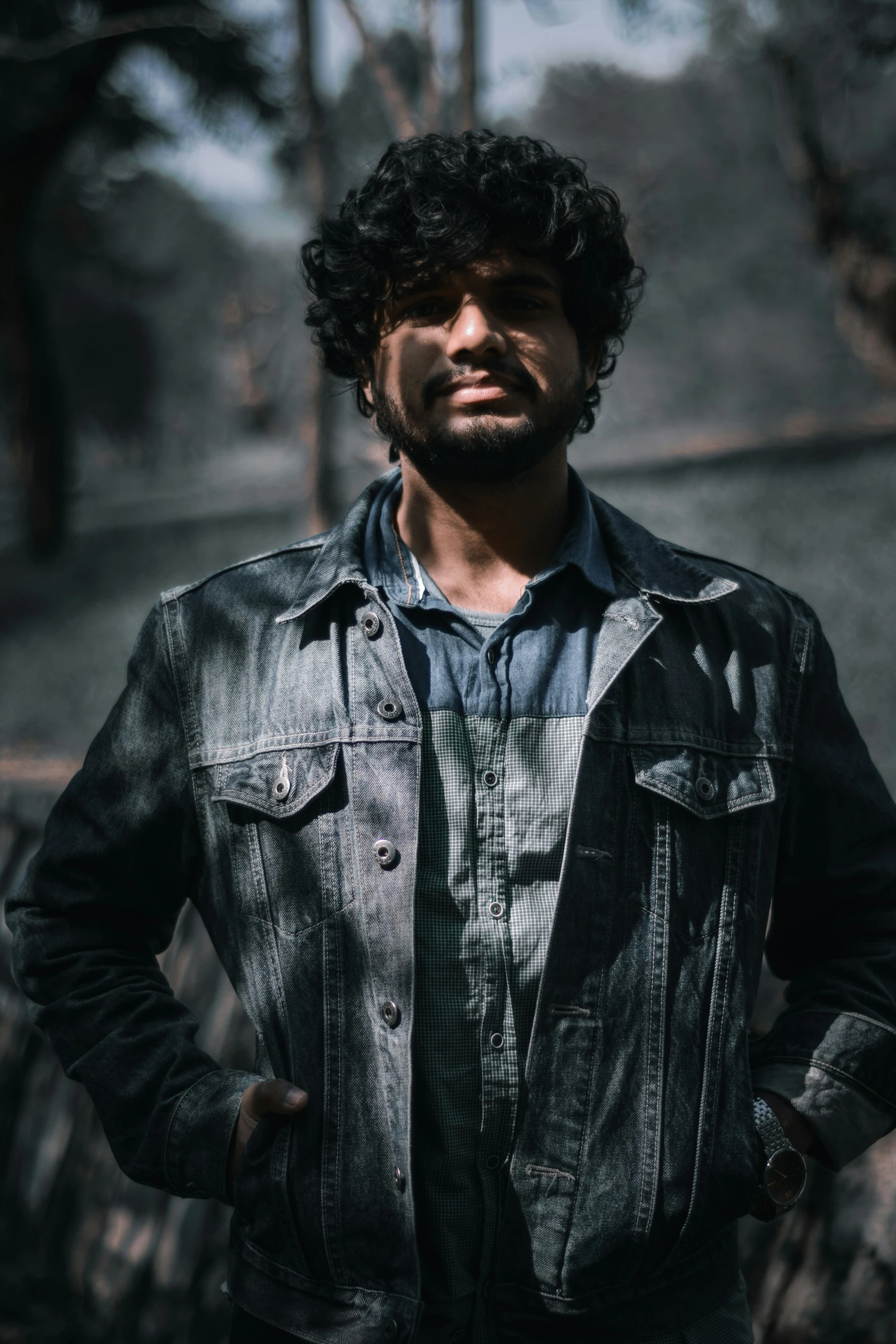 a bearded man in black jacket stands for a portrait