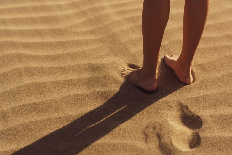 person standing in the sand on a beach with their toes in sand