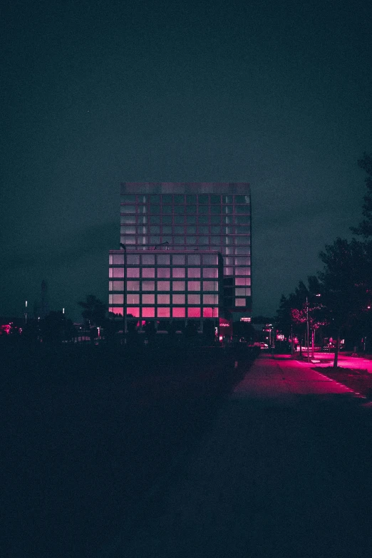 dark city at night, with large building behind a glowing fence