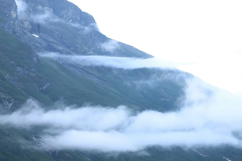 a mountain with fog, and some trees on it