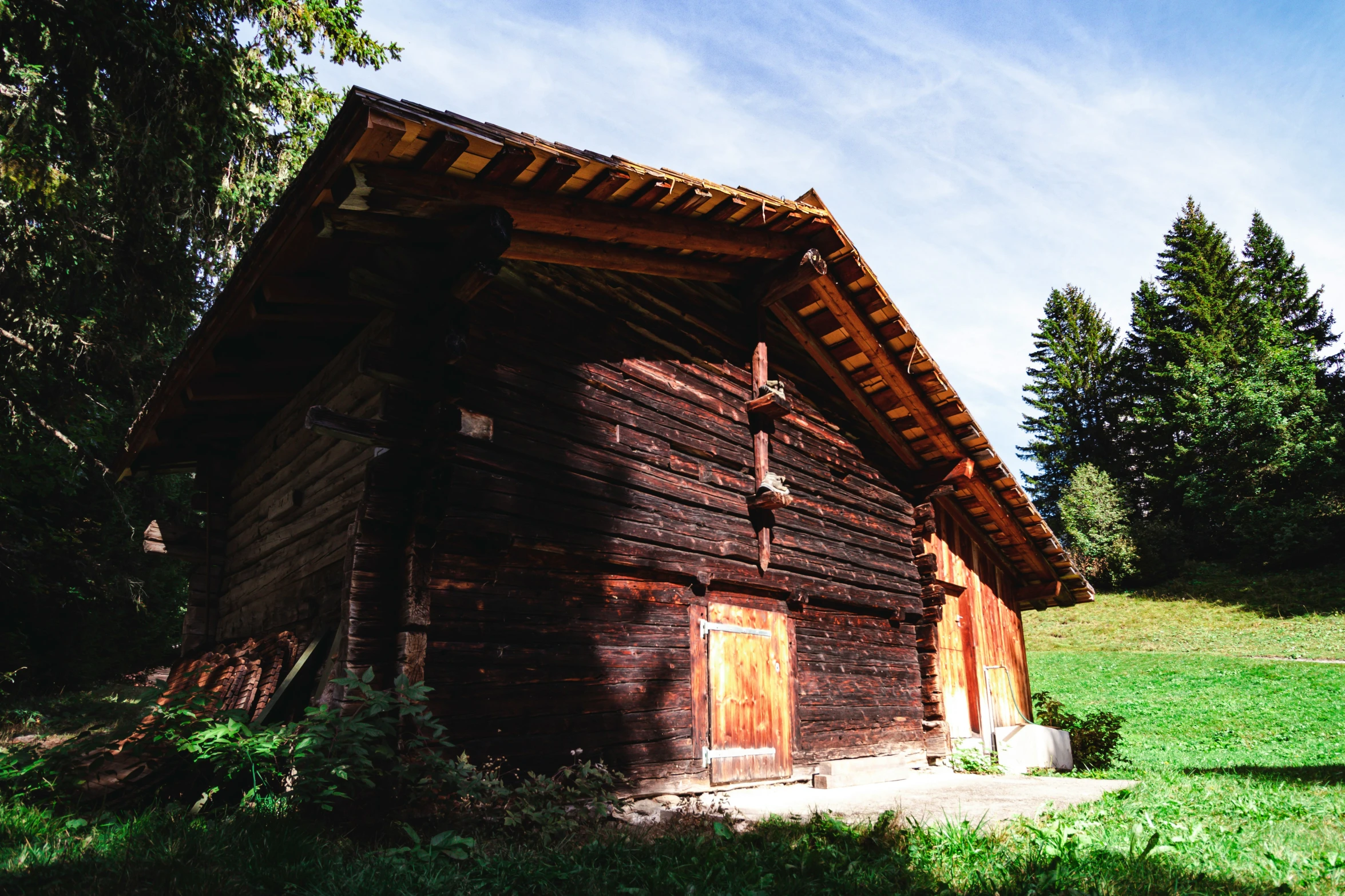 an old log cabin sits in the middle of the grass