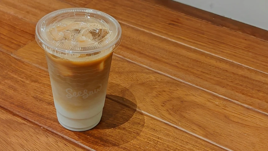 a drink on a wooden table with the lid partially covered